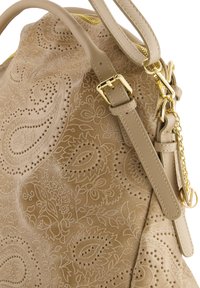Beige lædertaske med præget blomster- og paisleymønster. Har en gylden lynlås, justerbar rem og kædeaccent. Strukturér overflade.