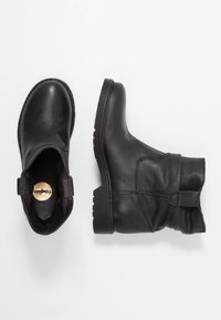 Czarne skórzane botki za kostkę o fakturowanej powierzchni, z niskimi obcasami na klocku i luźnym mankietem. Posiadają okrągły nosek i płaską gumową podeszwę.