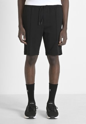 Shorts deportivos negros con cintura elástica y cordón, con dos pliegues frontales y un sutil detalle del logo en el lado.