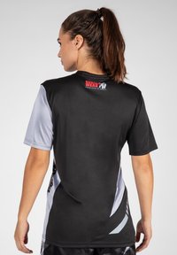 Zwart en grijs sportshirt met korte mouwen. Heeft een logo op de bovenrug en een slanke fit met contrasterende zijaccenten.