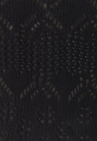 Stickad tyg i svart med en texturerad, öppen mönstring som har geometriska former och en slät yta, vilket framhäver olika sticktekniker.