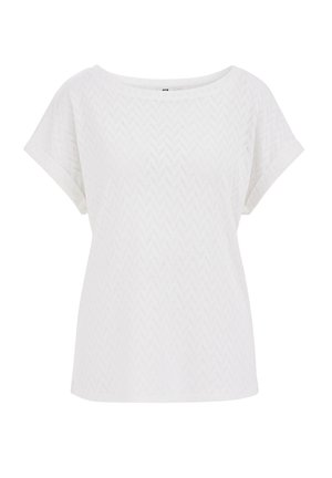 Haut blanc à manches courtes en tissu texturé avec un motif en zigzag, doté d'un large col rond et d'une coupe décontractée.