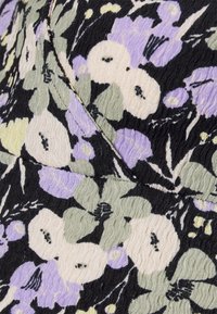 Tecido floral com flores roxas, verdes e creme sobre um fundo preto. Texturizado, com costuras visíveis e um padrão ondulado.