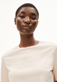 Lichtroze t-shirt met een ronde hals, korte mouwen en een zachte stofstructuur, nauwsluitend om het lichaam, minimalistisch ontwerp, glad oppervlak.