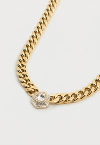 Χρυσό κολιέ αλυσίδα με μεγάλο εξάγωνο μενταγιόν που διαθέτει καθαρό πολύτιμο λίθο περιτριγυρισμένο από μικρούς διάφανους λίθους. Λεπτό, γυαλιστερό μεταλλικό φινίρισμα.