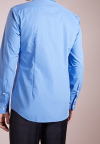 Lichtblauw overhemd met lange mouwen, een gladde textuur, knoopmanchetten en een gebogen zoom, voorzien van een strak design aan de achterkant en zijnaden.