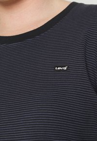 T-paita tummansinisillä raidoilla, mustalla kauluksella, jossa on pieni valkoinen Levi's-logo vasemmalla puolella. Puuvillamateriaalia, rento istuvuus.