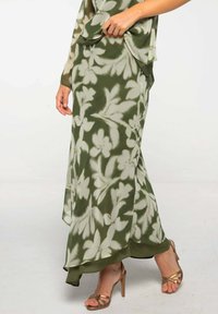Falda maxi floral verde hecha de un tejido ligero, con un diseño fluido que presenta patrones de flores blancas y un dobladillo que cae de manera elegante.