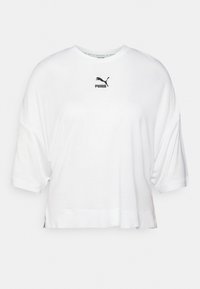 T-shirt bianca cropped realizzata in morbido cotone, con scollatura rotonda e maniche corte. Logo Puma nero in evidenza sul petto.