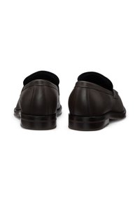 Mocasines de cuero marrón oscuro con un acabado suave, tacón bajo y apilado, y punta redondeada. Costuras visibles y un detalle de marca sutil.