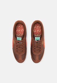 Baskets en daim marron et textile avec des accents orange. Dotées d'une semelle intérieure texturée et du logo Puma vert. Fermeture à lacets, bout arrondi.