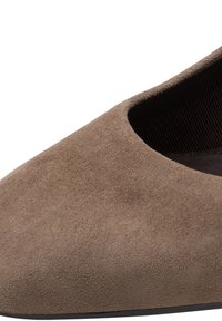 Gros plan d'une chaussure plate en daim marron à bout pointu avec doublure intérieure noire côtelée et semelle basse noire.