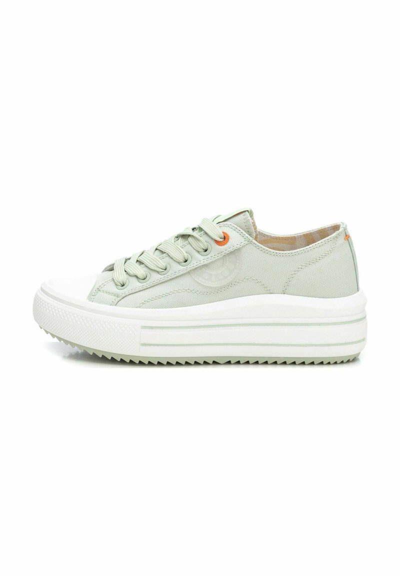 Zapatilla de lona verde claro con puntera de goma blanca, suela blanca gruesa y patrón de tracción texturizado. Presenta cordones planos y acentos en naranja.
