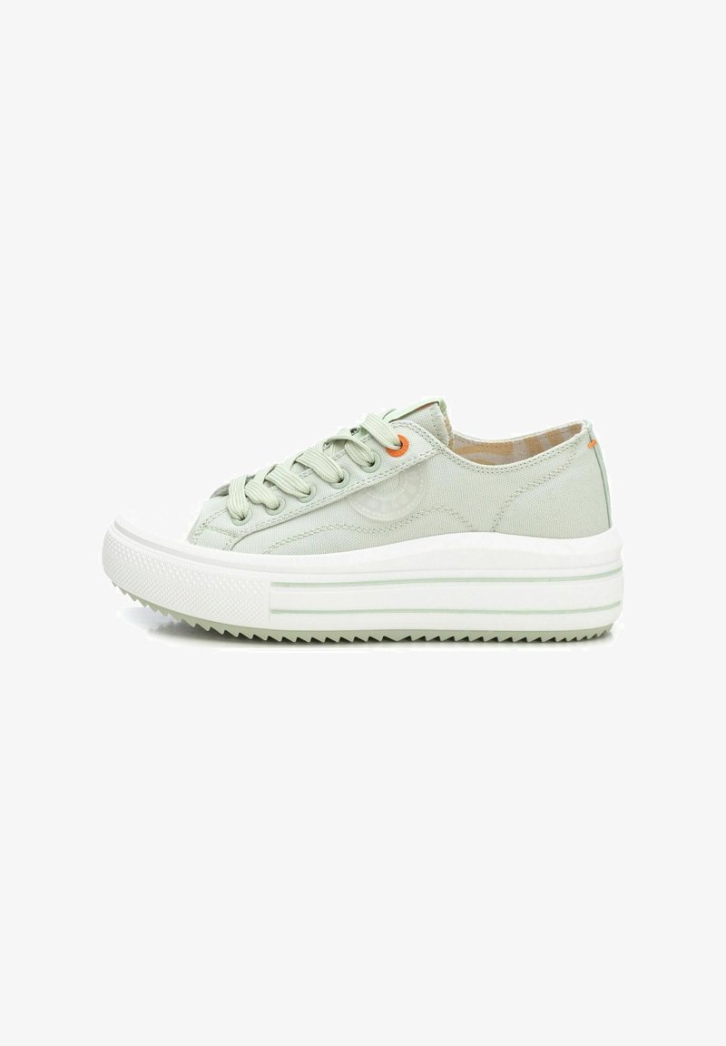 Zapatilla de lona verde claro con puntera de goma blanca, suela blanca gruesa y patrón de tracción texturizado. Presenta cordones planos y acentos en naranja.