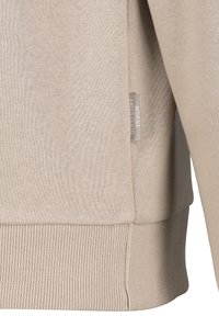 Beige Sweatshirt aus weichem Material, mit gerippten Bündchen und Saum sowie einem seitlichen Etikett mit der Aufschrift "Good Stuff Design."