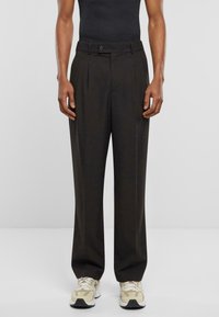 Pantalones plisados negros fabricados con un tejido suave. Cuentan con una cintura ajustada con cierre de botón y un diseño de pierna recta.