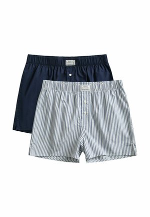 Twee herenshorts, één effen donkerblauw en één wit met blauwe strepen, beide met elastische taillebanden en knopen aan de voorkant.