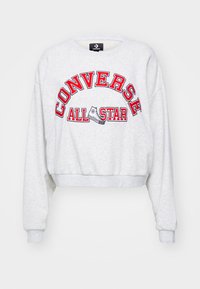 Sudadera gris corta con mangas largas que presenta el texto bordado en rojo "CONVERSE ALL STAR" y un gráfico de una zapatilla en el frontal.