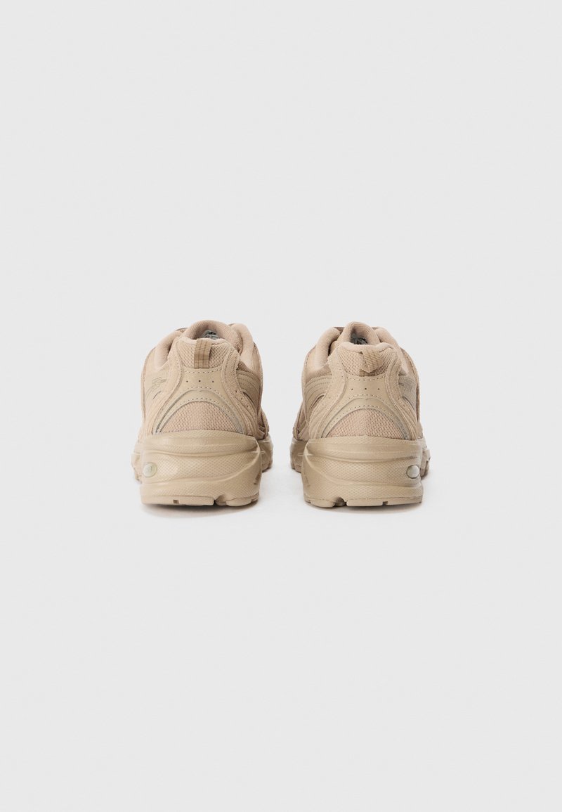 Beige Laufschuhe mit einem strukturierten Mesh-Obermaterial, gepolsterter Sohle und verstärktem Fersenhalt. Mit dezenten Nähten und Branding-Details.