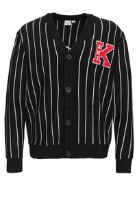 Svart cardigan med hvite vertikale striper, v-hals, fem svarte knapper og et rødt brodert bokstav "K" på venstre side.