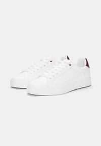 Sneaker bianche in pelle liscia, con design low-top, lacci piatti e un accento sul tallone di colore viola. Sole testurizzato per una migliore aderenza.