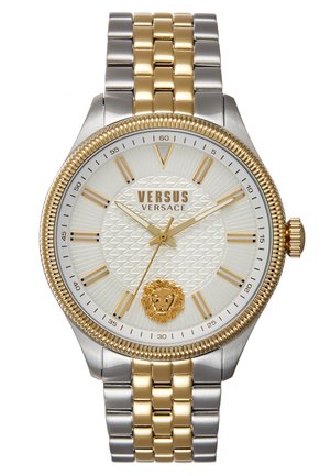 Montre-bracelet Versus Versace avec bracelet métal argenté et doré, cadran blanc texturé, index dorés, aiguilles et emblème du lion à 6 heures.