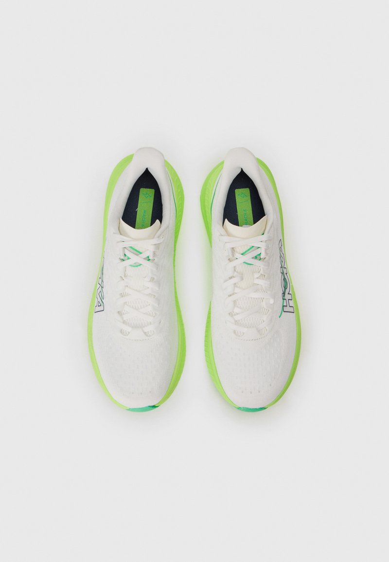 Vita idrottsskor i vitt med en strukturerad ovandel, gröna detaljer och en tjock sula. Har snörning, logotyp på sidan och en vadderad innersula.