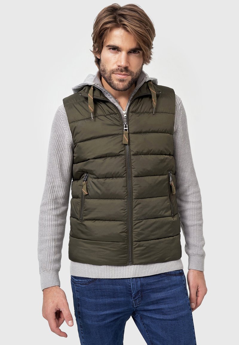 Olivenfarvet polstret vest med lynlåslukning, der har sidelommer og hætte. Den indre lag er grå, med et tekstureret, ribbet ærmedesign.