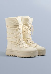 Kremowe, ocieplane buty zimowe z teksturowaną powierzchnią, sznurowanym designem i grubą gumową podeszwą zapewniającą przyczepność i ciepło.