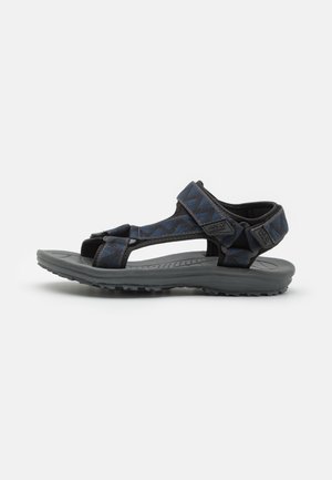 Schwarze und blaue Sandalen für den Außenbereich mit verstellbaren Riemen, strukturiertem Fußbett und einer robusten grauen Sohle mit einem Profilmuster für besseren Halt.