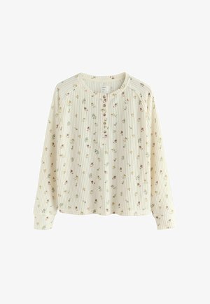 Top crema a maniche lunghe con texture a coste, stampa floreale in rosa e verde, scollo rotondo, patta con bottoni e vestibilità morbida.