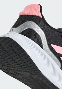 Black athletic shoe featuring a mesh upper, silver accents, pink heel tab, and white midsole with textured black rubber outsole.