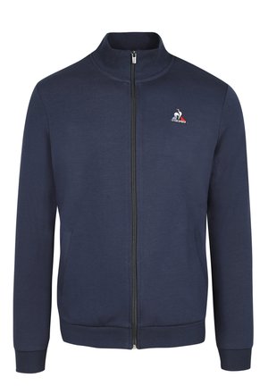 Navy zip-up jack in zachte stof, met een hoge kraag, twee voorzakken en een klein geborduurd logo op de linkerkant van de borst.