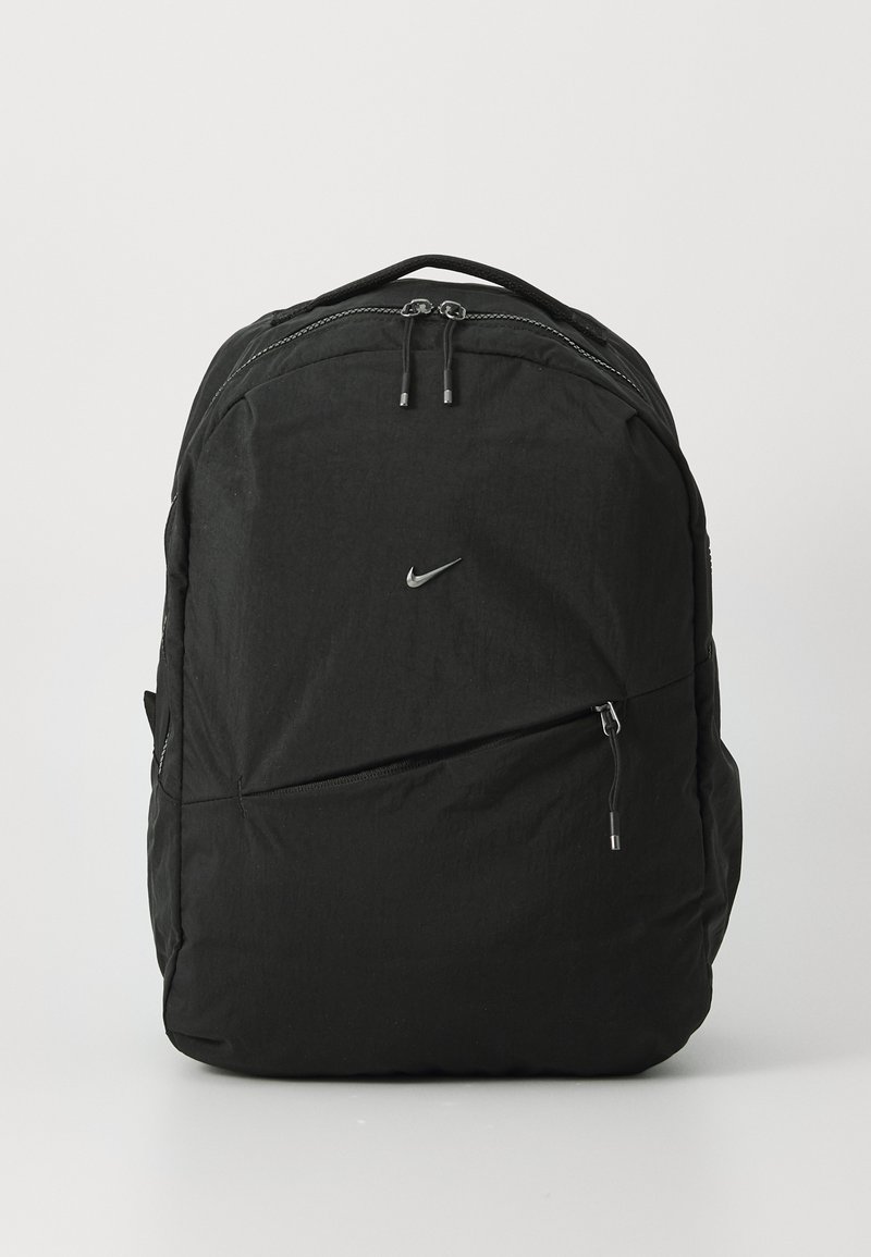 Svart Nike ryggsekk laget av lett stoff, med et stort hovedrom, frontlomme med glidelås og justerbare skulderremmer.
