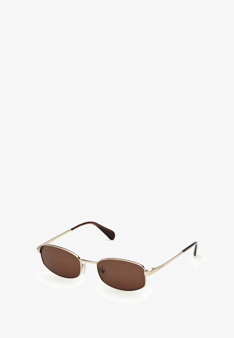 Sunglasses with oval brown lenses, thin gold metal frame, and dark brown temples. Features nose pads for comfort. Minimalist design.