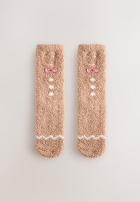 Bruine pluizige sokken met een peperkoekontwerp, met een glimlachend gezicht, rode geruite strik en witte knoopdetails. Zachte textuur.