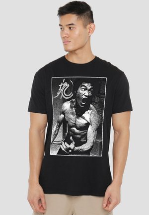 Black cotton t-shirt featuring a graphic print of a muscular figure in a monochrome distressed style, set within a rectangular border.
