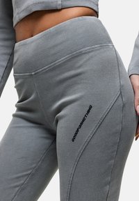Grijze geribbelde leggings met een hoge tailleband en zijnaaddetails. "GOOD FOR NOTHING" logo in zwart op de linker bovenbeen.