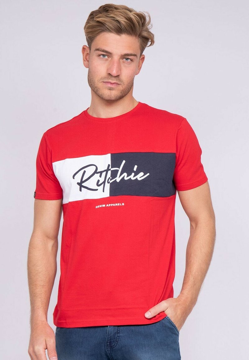 T-shirt en coton rouge avec une bande horizontale blanche et marine portant le logo "Ritchie". Manches courtes et col rond ; coupe décontractée.