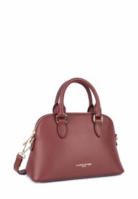 Piccola borsa a tracolla in pelle bordeaux con parte superiore arrotondata, hardware dorato, doppio manico e tracolla removibile. Texture liscia con una leggera grana.