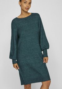 Abito lavorato a maglia teal con scollatura a barca, maniche oversize e polsini a coste. Il tessuto presenta un aspetto strutturato e una silhouette dritta.