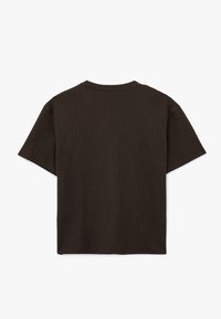 Camiseta de manga corta color marrón oscuro con cuello redondo, hecha de una tela texturada, con un diseño simple y rectangular sin adornos.