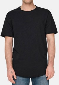 Schwarzes T-Shirt mit kurzen Ärmeln, geripptem Rundhalsausschnitt und rohen Kanten, das einen lockeren Schnitt und einen weichen, strukturierten Stoff aufweist.