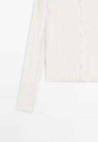 Cardigan bianco a coste con chiusura a bottoni e maniche lunghe. Texture morbida, design cropped e dettagli sottili lungo i bordi.