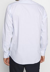 Světlomodrá kostkovaná košile s dlouhým rukávem, manžetami na knoflíky, jemnou texturou a zaobleným lemem, navržená pro přiléhavý střih.