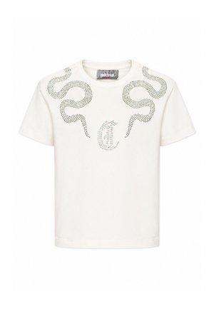Camiseta blanca de manga corta con patrones de serpiente con tachuelas plateadas en los hombros y el pecho, con una etiqueta de marca en el interior del cuello.