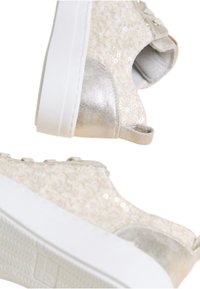 Sneakers beige chiaro con una tomaia testurizzata decorata con paillettes, dettagli argentati e una spessa suola in gomma bianca, progettati per un uso casual.