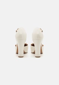 Weiße High Heels aus glattem Leder mit abgerundeter Zehenpartie, einem klobigen Absatz und einem seitlichen Schnallenverschluss.