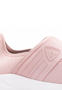 Světle růžová sportovní bota z texturované síťoviny, s logem a třemi prodlouženými pruhy na straně, s bílou podrážkou.