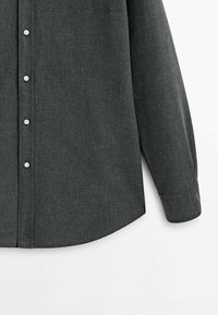 Chemise grise foncée à manches longues avec boutons blancs, vue de face et de la manche droite sur fond blanc.